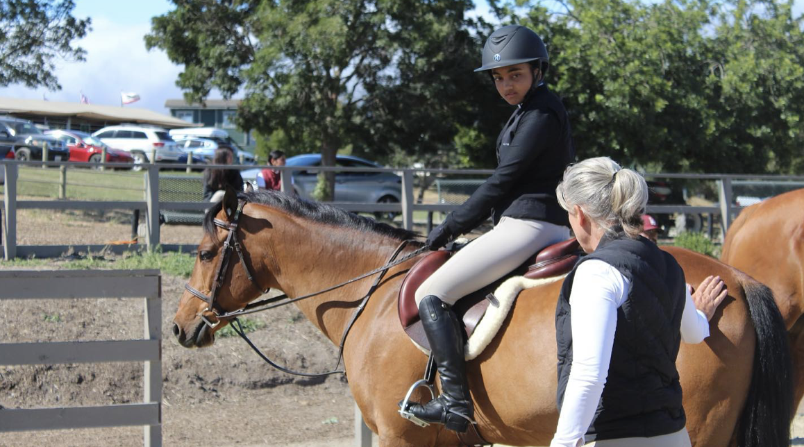 Kelly coaching a young rider at a show. Photo courtesy of Kelly Maddox